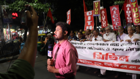 A television reporter moves quickly as the protesters progress behind him A television reporter moves quickly as the protesters progress behind him